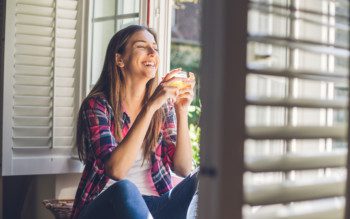 Viver sem ar condicionado - Mulher aproveita ar fresco que entra pela janela de casa