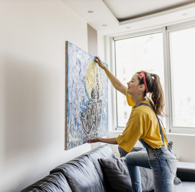 Mulher pendurando um quadro na parede.
