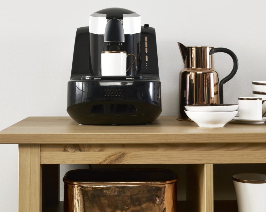 Imagem de um cantinho do café com cafeteira, bule e pratos.
