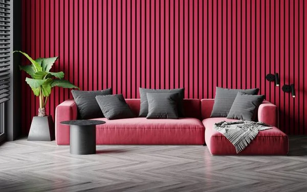 Imagem de uma sala de estar com painel ripado de madeira pintado na cor Magenta e sofá na mesma cor com almofadas cinzas. 