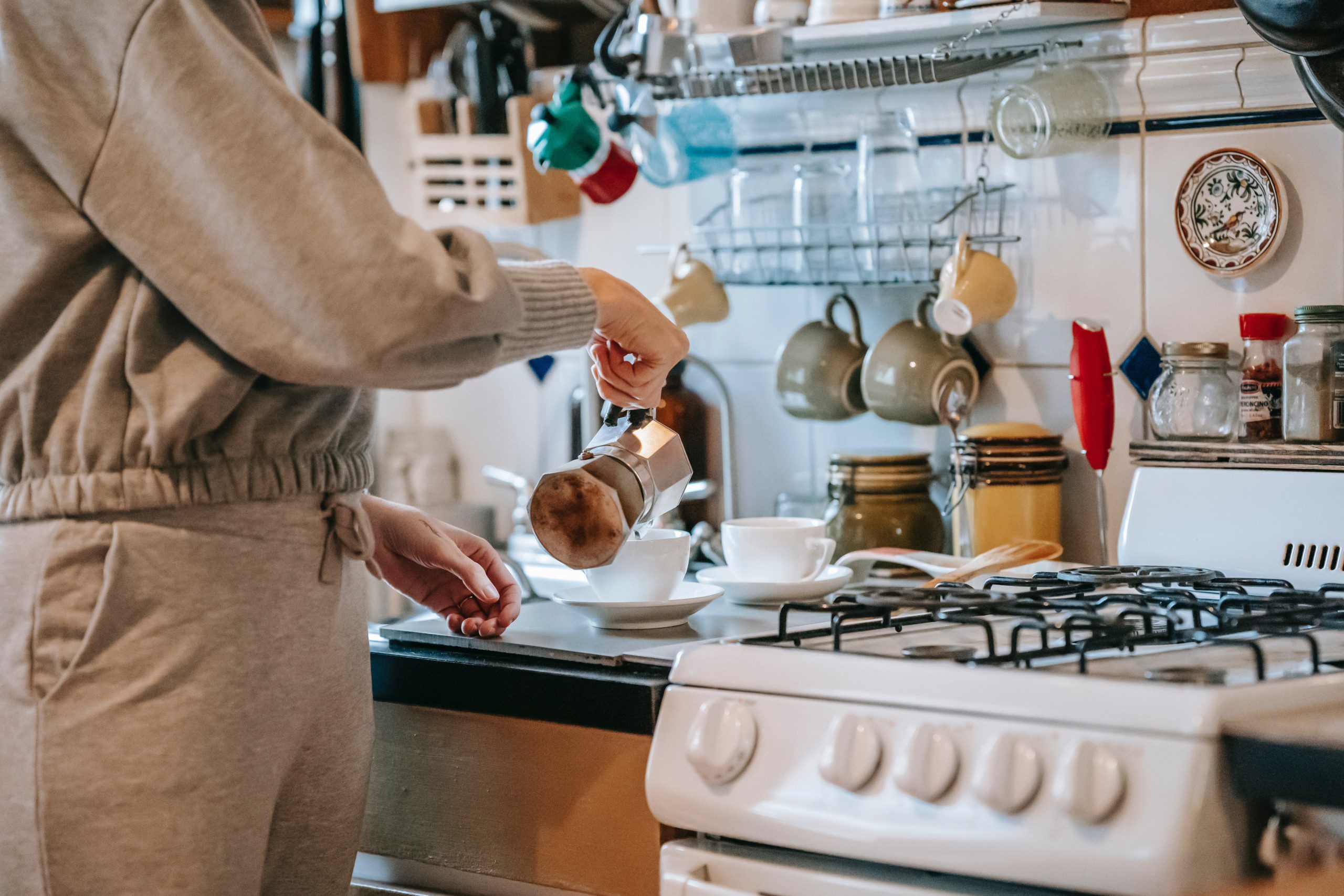 Imagem de uma mulher preparando um café em uma bancada de cozinha.