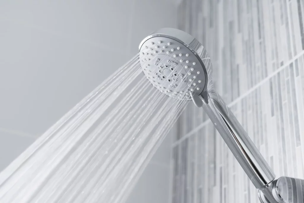 Imagem de um chuveiro moderno em material metálico ligado com água saindo para ilustrar matéria sobre a troca de titularidade de água Sabesp