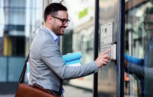 Em direção à portaria virtual, um homem sorri enquanto aperta um botão para entrar no condomínio.