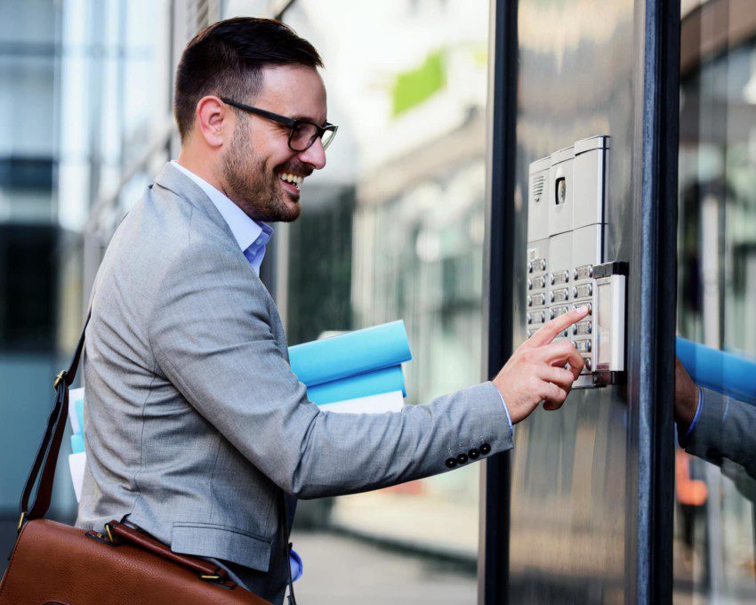 Em direção à portaria virtual, um homem sorri enquanto aperta um botão para entrar no condomínio.