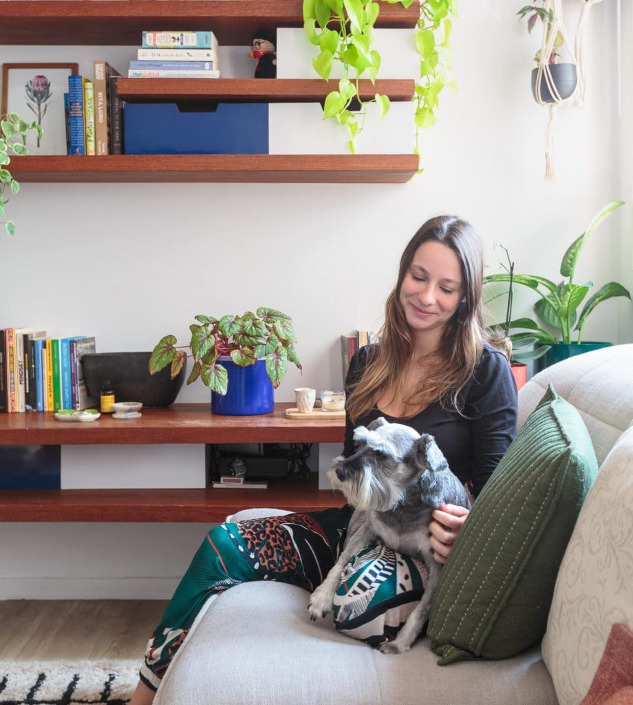Sentada no sofá em seu apartamento de 1 dormitório na Pompéia, a publicitária Giulia acaricia sua cachorrinha Lucy.