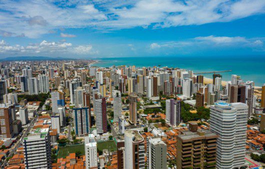 Foto que ilustra matéria sobre o custo de vida em Fortaleza mostra os prédios da cidade com o mar azul ao fundo.