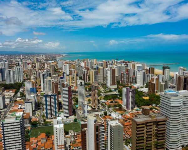 Foto que ilustra matéria sobre o custo de vida em Fortaleza mostra os prédios da cidade com o mar azul ao fundo.
