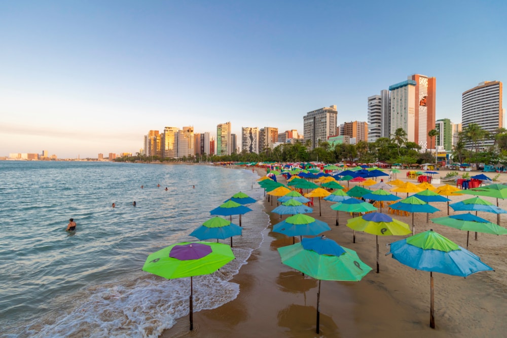 Foto que ilustra matéria sobre os bairros nobres de Fortaleza mostra a Praia de Meireles com guarda-sóis coloridos.