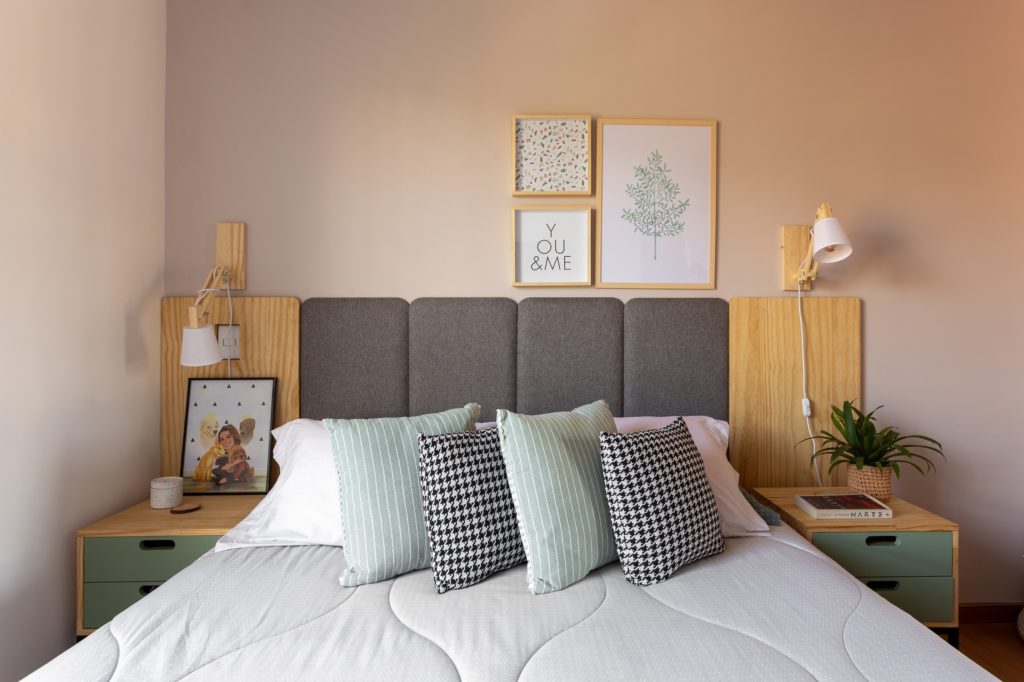 Foto que ilustra matéria sobre apartamento no Jardim Prudência mostra uma cama de casal com almofadas de estampas listradas e zebradas, com duas meses de cabeceira e quadros na parede