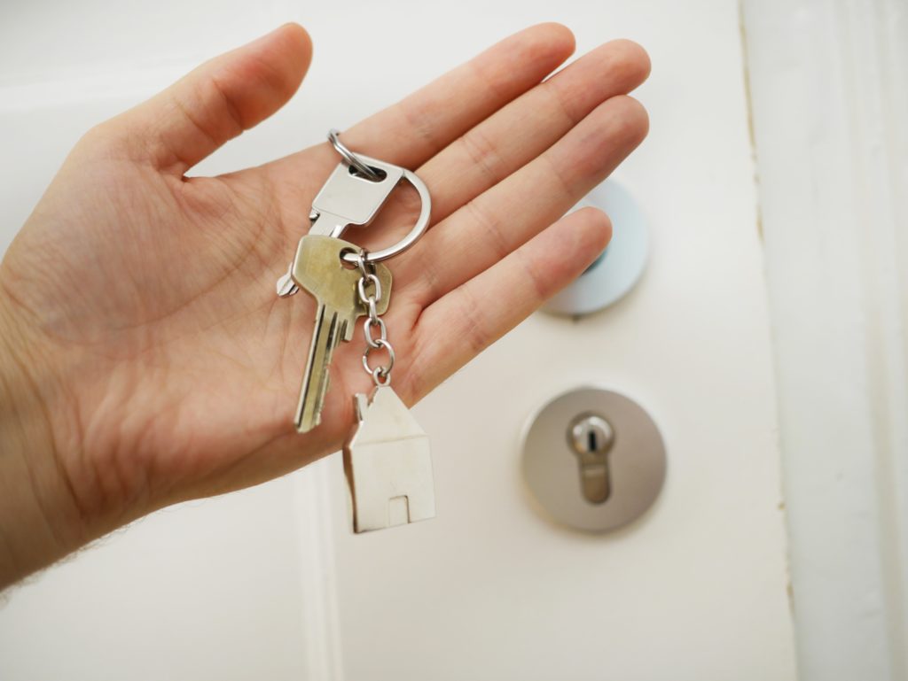 imagem de alguém segurando chaves de uma casa ou apartamento em frente à entrada