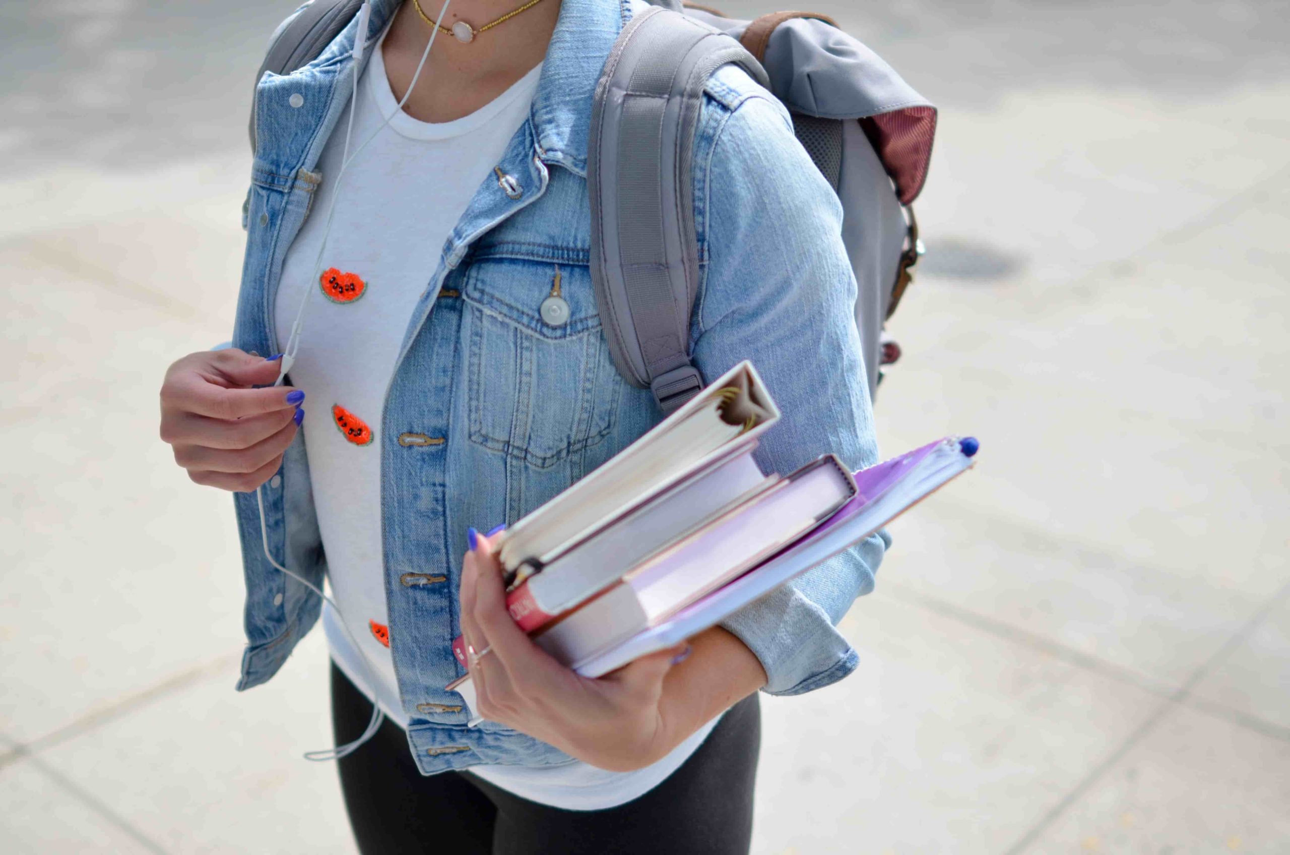 imagem de uma estudante com mochila nas costas e livros nas mãos
