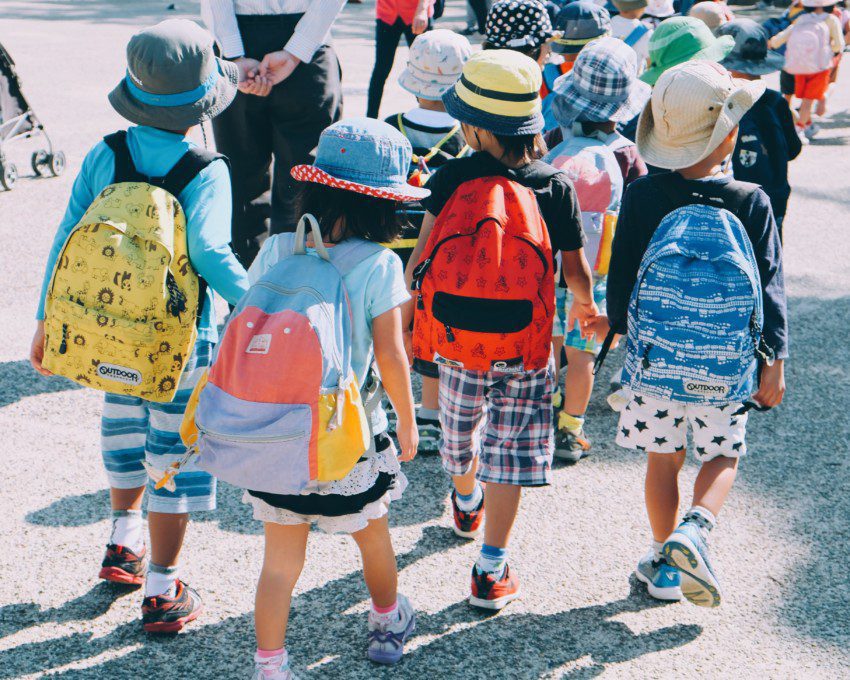 grupo de crianças andando na rua, usando mochilas escolares e roupas coloridas — capa do conteúdo sobre as melhores escolas particulares do Rio de Janeiro