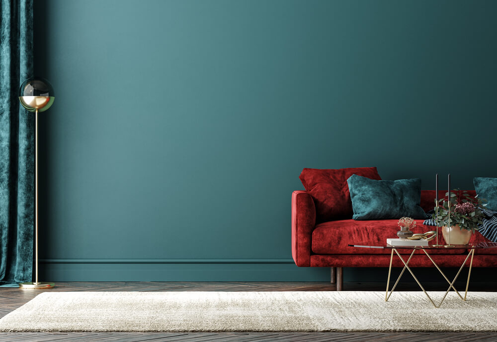 Exemplo de uma sala com parede verde compondo com a cor análoga vermelha do sofá