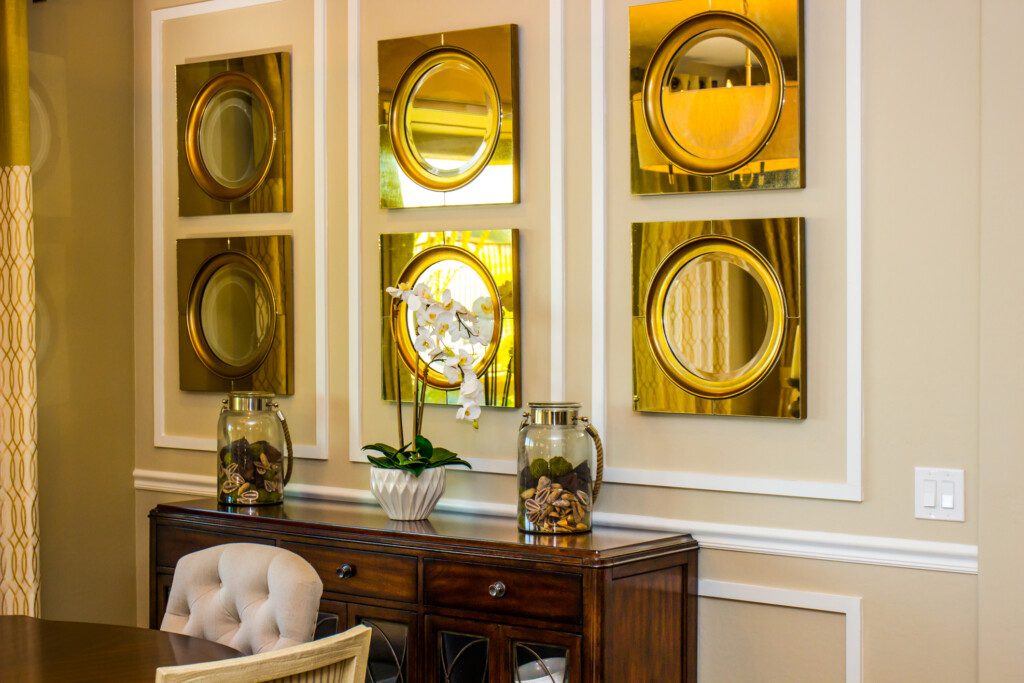 Sala de jantar com 6 pequenos espelhos dourados em cima de um armário. 