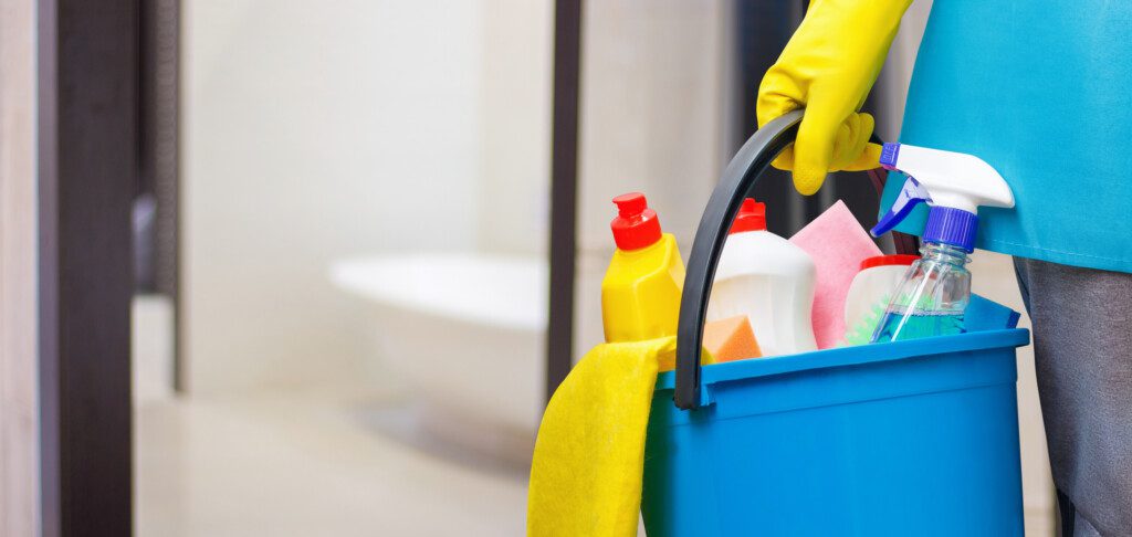 Foto que ilustra matéria sobre como limpar box de banheiro mostra uma pessoa segurando um balde com produtos de limpeza.