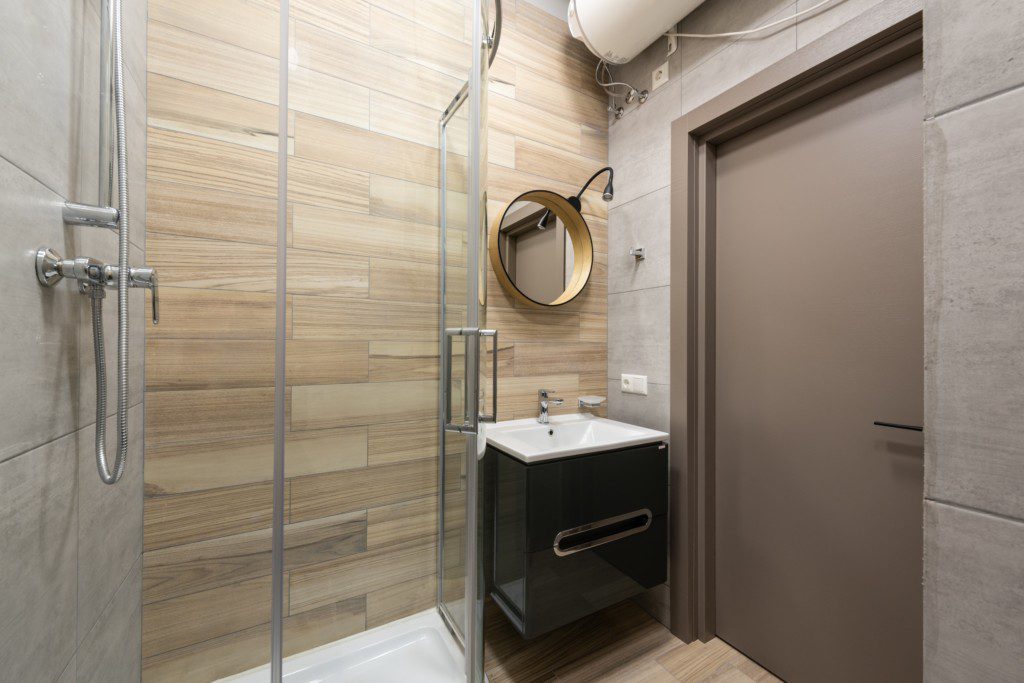 Foto de um banheiro pequeno decorado com espelho oval. Há também uma área para banho e uma pia com armário embutido.