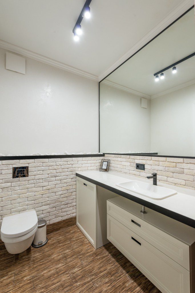 A foto mostra um banheiro pequeno com móveis planejados embaixo da pia. Os móveis são duas gavetas e um compartimento maior. Há também um vaso sanitário na imagem.