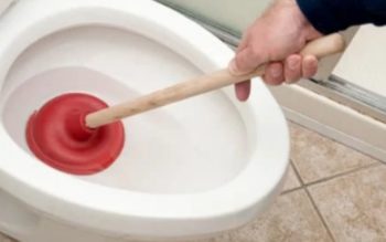 pessoa usando um desentupidor no vaso sanitário