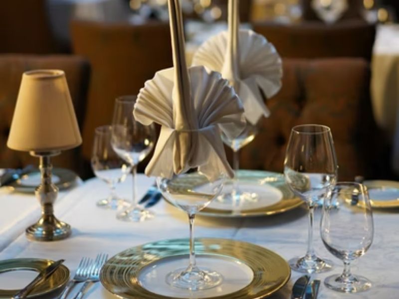 mesa posta para jantar, em tonalidades brancas e douradas