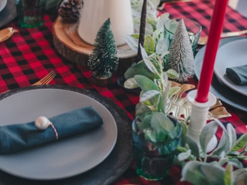 mesa posta com toalha xadrez vermelha e branca e decorações natalinas