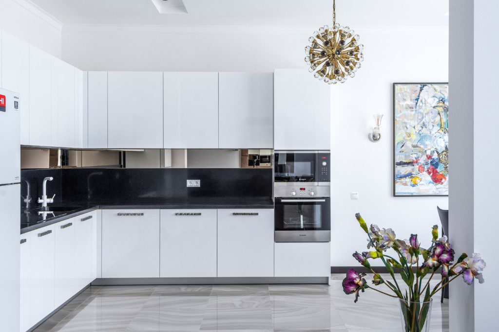 Armário de cozinha branco com detalhes em preto com espaço para eletrodomésticos de embutir. 