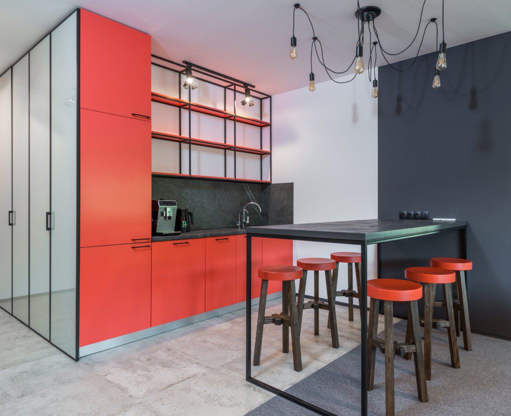 Armário de cozinha vermelho com detalhes em preto e itens decorativos em ferro. 