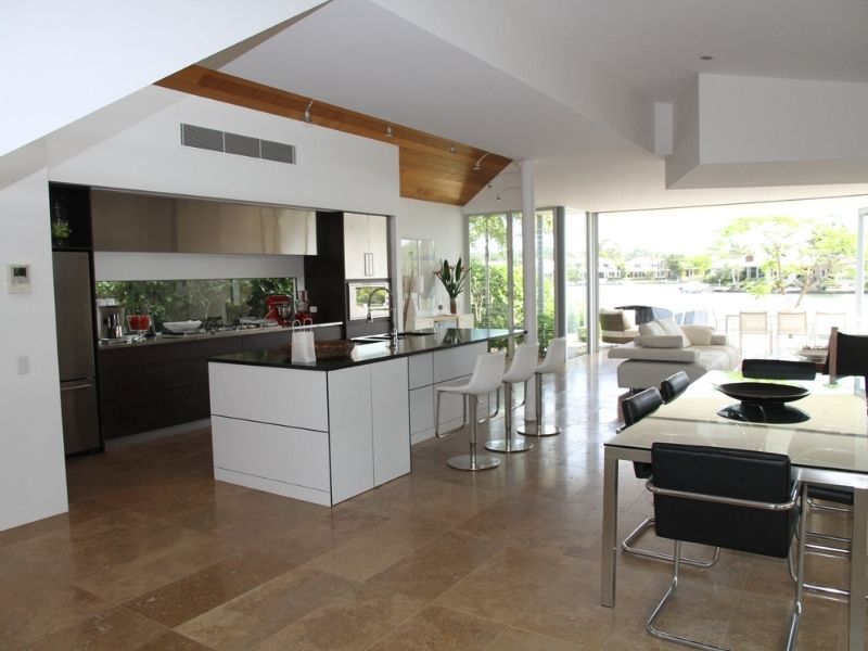piso de granito e mármore em cozinha ampla com abertura para área externa ao fundo, muita iluminação.