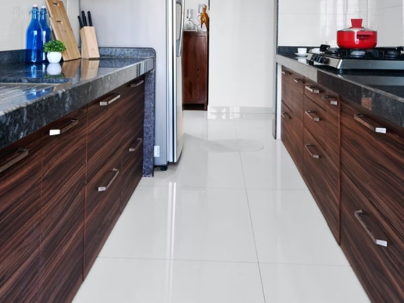 Cozinha comprida com piso epóxi branco e bancadas em madeira escura com tampo de pedra preta