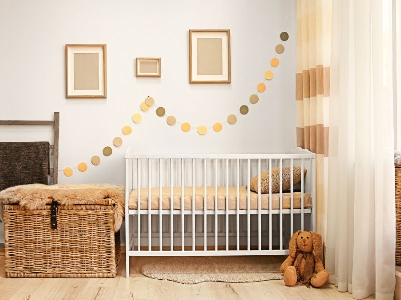 quarto de bebê com um berço, decorações em tons dourados e cortinas