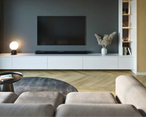 Sala de TV em tons neutros com cinza, bege e madeira.