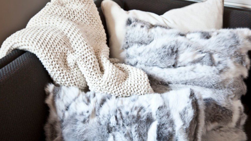 sofá coberto com manta e almofadas felpudas