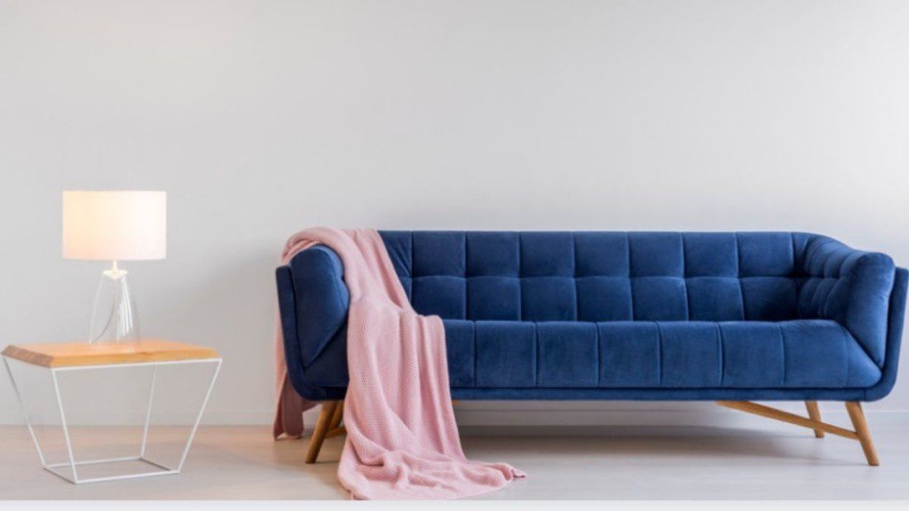 sofá azul de três lugares com uma manta lateral cor de rosa