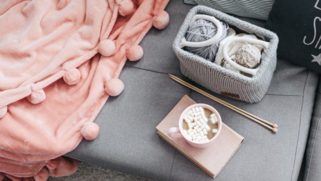 manta artesanal no sofá ao lado de um kit de crochê