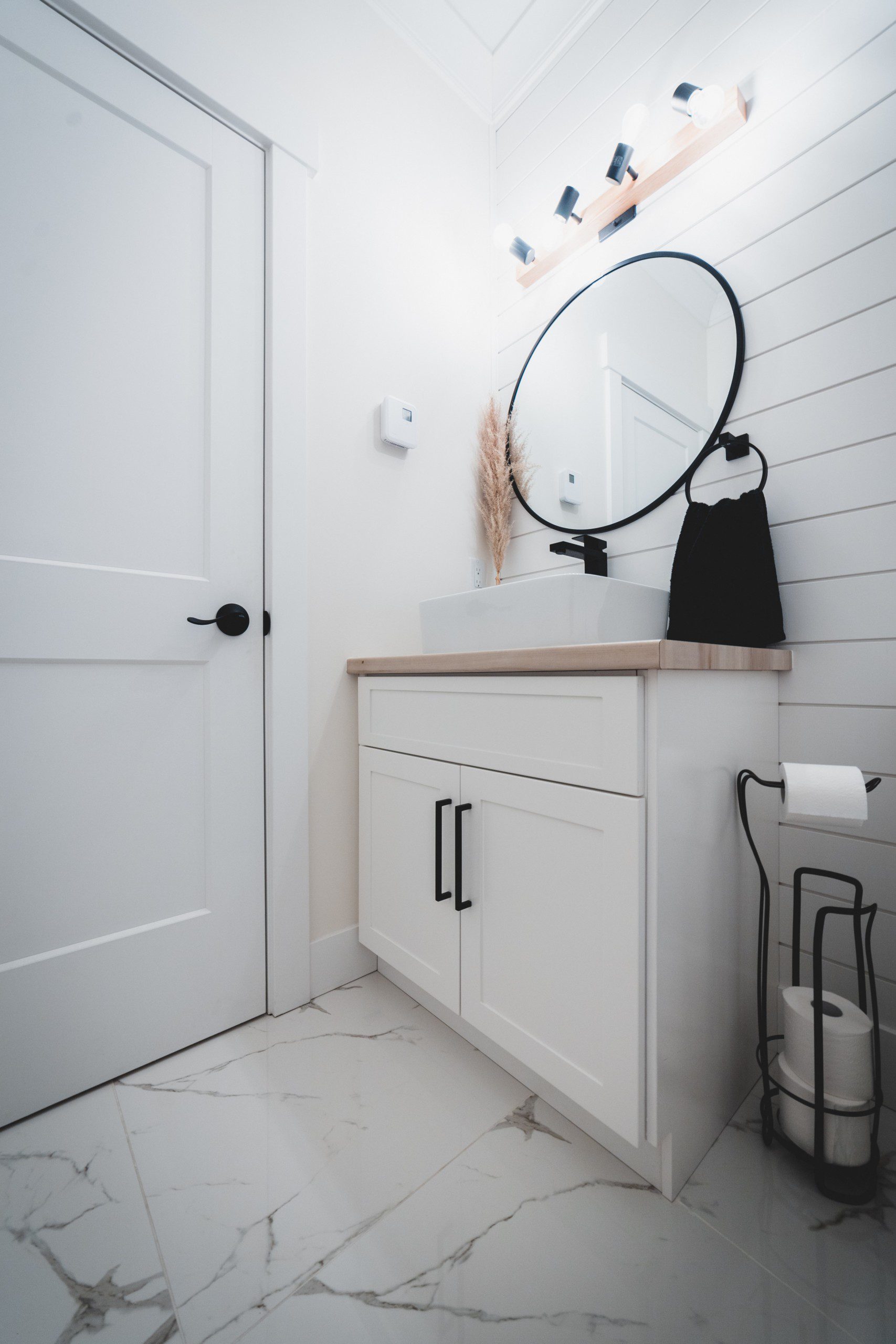 Lavabo pequeno estilo de decoração minimalista e escabinavo com armário de banheiro branco e detalhes em preto.