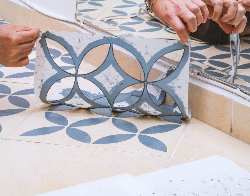 Foto que ilustra matéria sobre como fazer stencil mostra um detalhe de um molde de stencil sendo retirado de um piso após a aplicação de uma tinta azul.