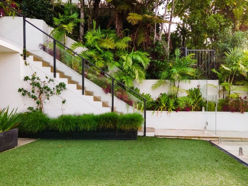 jardim externo com grama aparada e cerca viva próxima a uma escada, paisagismo no jardim aplicado