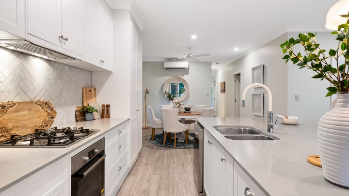 cozinha ampla com fogão, geladeira e armários, com as paredes na cor branca