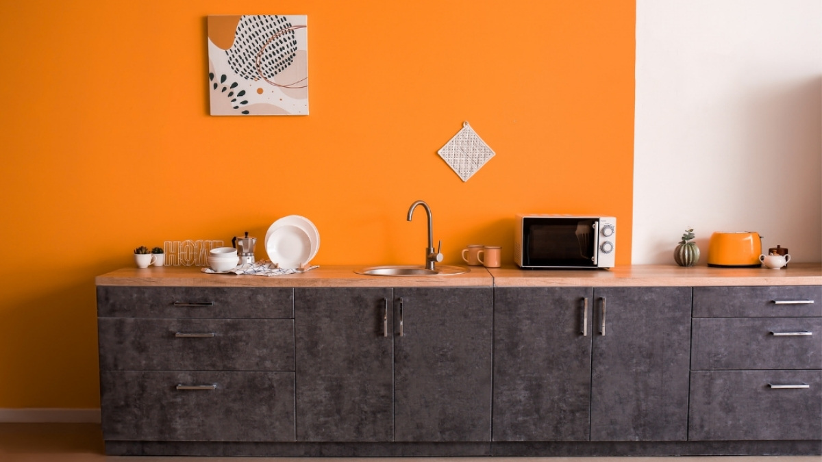 paredes de uma cozinha na cor laranja, com as bancadas combinando em um tom cinza escuro