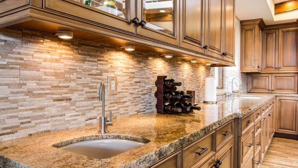 parede marrom de tijolos em uma cozinha, mostrando a pia, bancadas, armários de teto