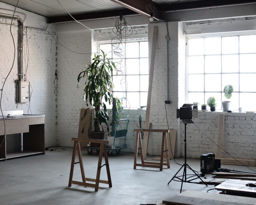 Imagem de um ambiente com tijolinhos na parede em tons de cinza, duas janelas e vários fios elétricos soltos na parede