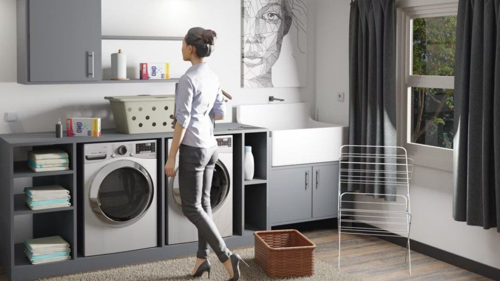 A imagem mostra uma mulher de pé em uma área de serviço moderna completa com máquina de lavar roupa, secadora e tanque.