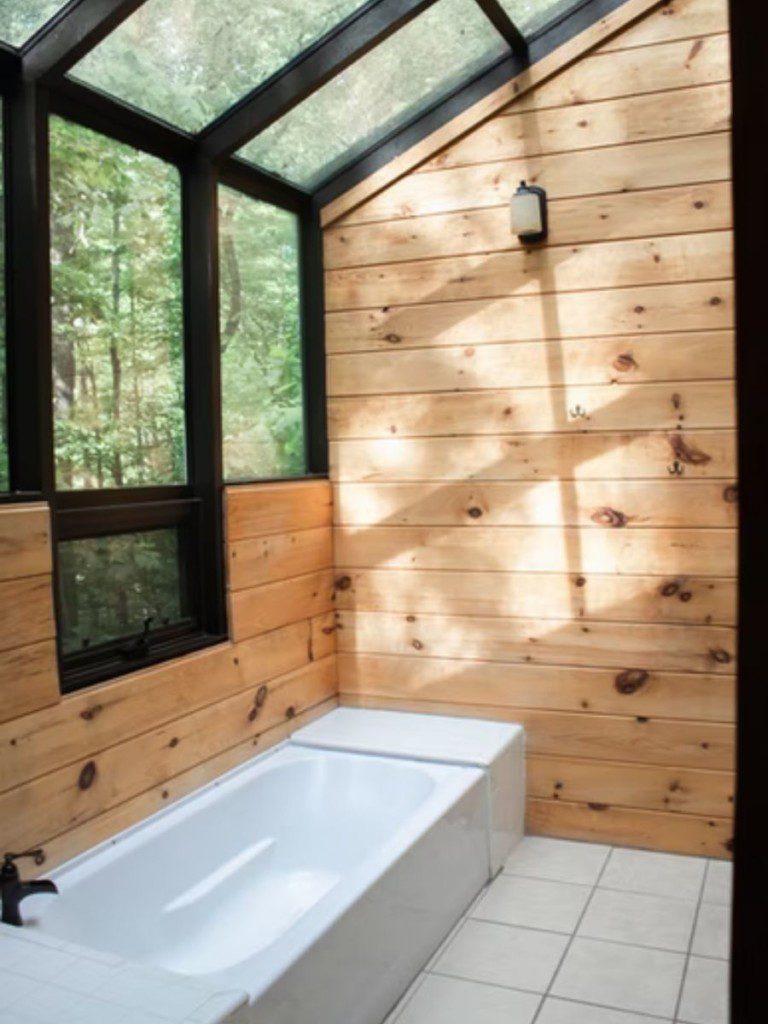 banheiro rústico com banheira e teto de vidro com iluminação natural