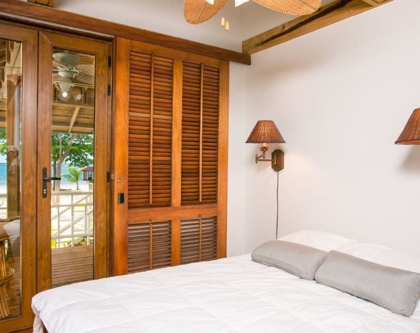 quarto de casa de praia com cama de casal e porta dupla com vista para o mar