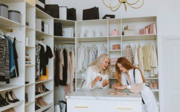 Imagem de duas mulheres escolhendo acessórios no closet.