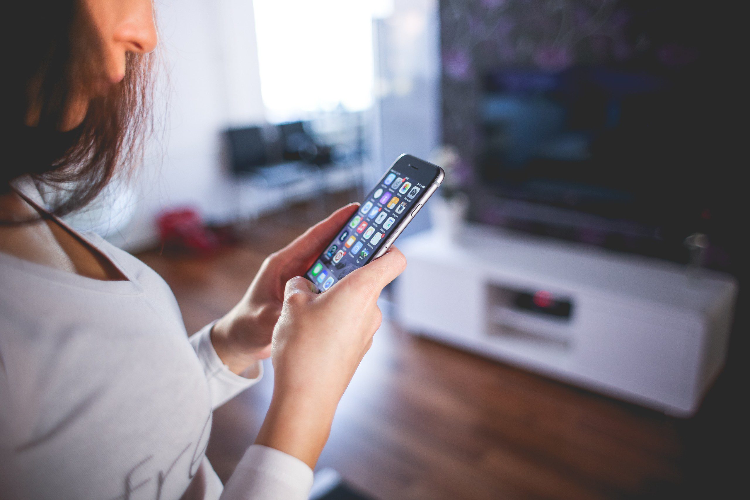 Imagem de uma mulher segurando um smartphone com diversos aplicativos na tela.