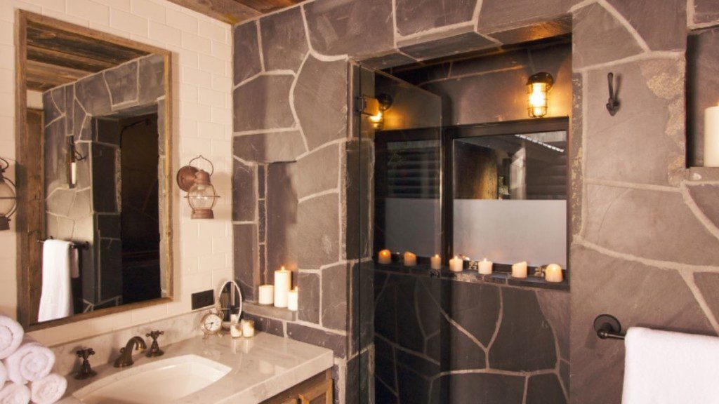 banheiro com revestimento em pedras, pia ampla e espelho retangular