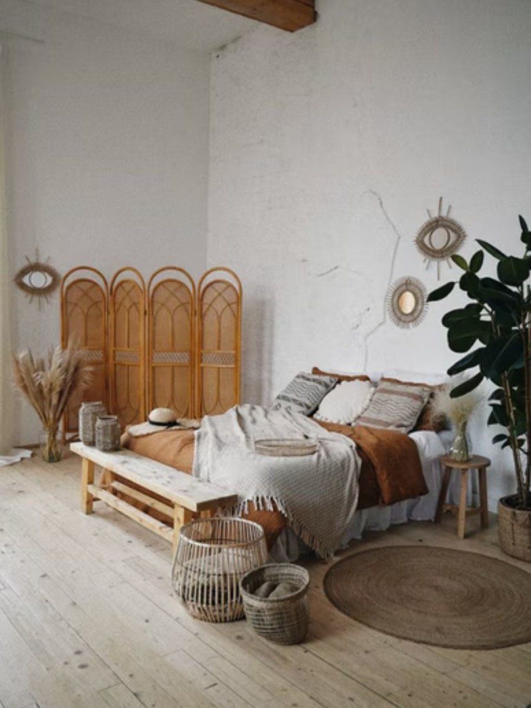 cama de casal no centro de um quarto rústico com tons terrosos e neutros