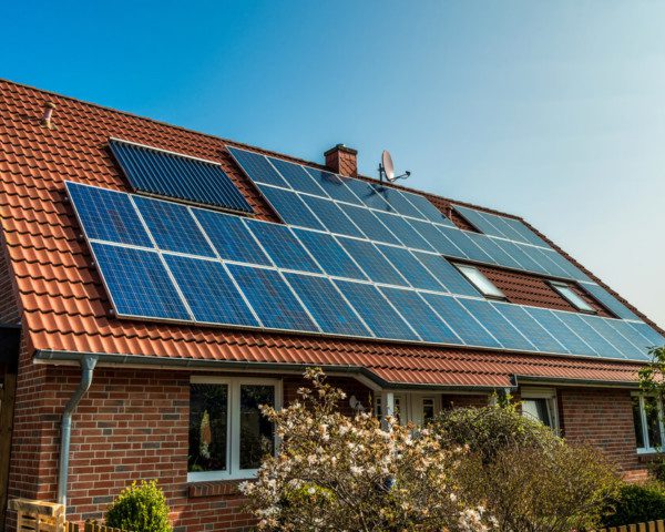 Foto que ilustra matéria sobre casas sustentáveis mostra uma casa vista de lado, com detalhe para o seu telhado quase que totalmente coberto por painéis de captação da luz solar para transformação em energia fotovoltaica.