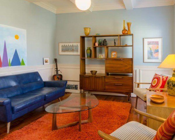 sala decorada em estilo vintage com sofá azul, armário de madeira, chão laranja