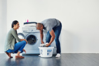 Foto que ilustra quiz de casal para o Dia dos Namorados mostra um casal lavando roupa em casa